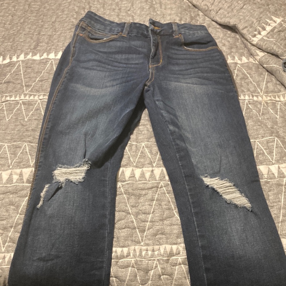 Dark blue straight legged stretchy jeans with frayed holes on front